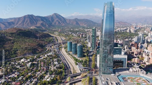 Aerial view moving right to reveal the Gran Torre Santiago skyscraper, modern glass buildings, and the Mapocho River in the Providencia district