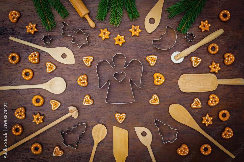 Fototapeta premium Baking holiday cookies with tools and decorations on a wooden table surrounded by pine branches