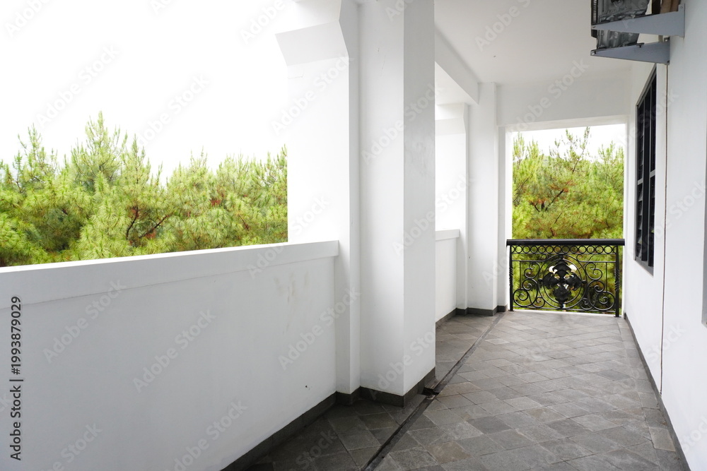 Fototapeta premium Empty balcony with tiled floor and view of pine trees in the background