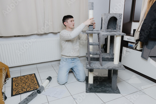 A man is assembling a new cat house in the living room.