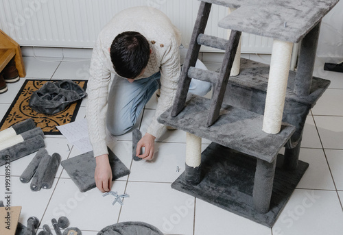 A man is assembling a new cat house at home.