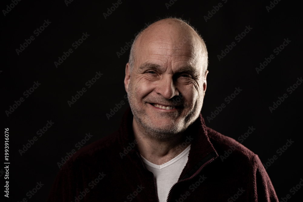 Obraz premium Middle aged bald man smiling broadly, radiating kindness and positive energy