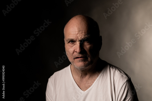 Man looking at camera with serious and worried expression in dark setting