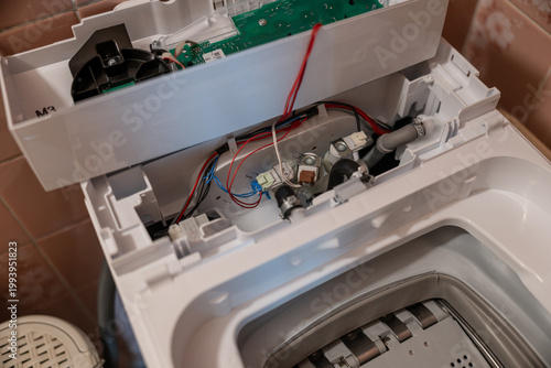 Close-up of water inlet solenoid valves inside an uncovered top-loading washing machine.
