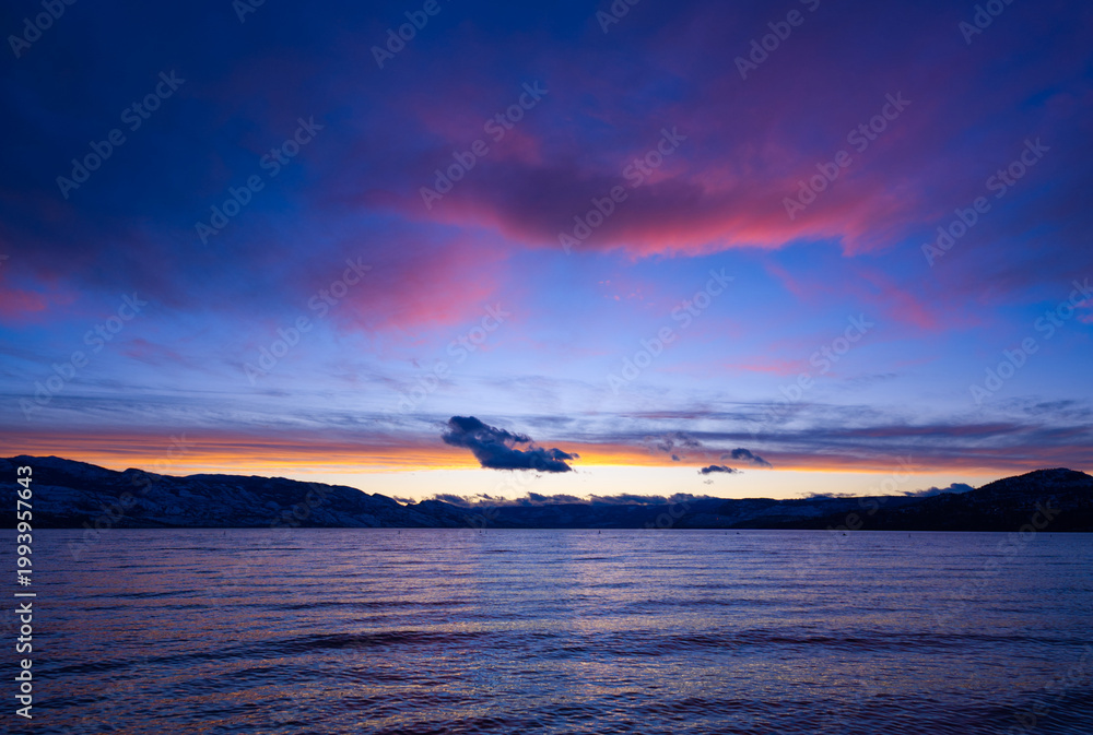 Fototapeta premium Vibrant blue and purple coastal scene with mountains and clouds