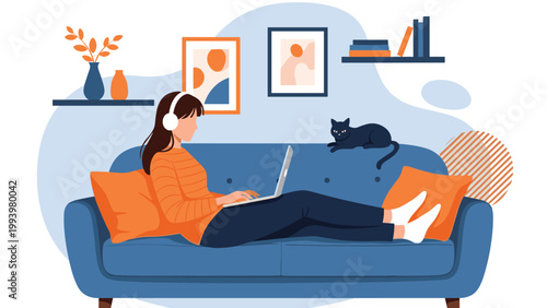 Young woman relaxing on a large blue sofa and using a laptop with headphones while a black cat sits beside her in a living room.