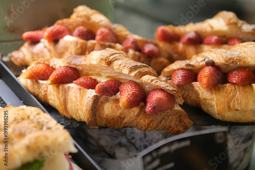 Billede på lærred Freshly baked croissants with strawberries on display