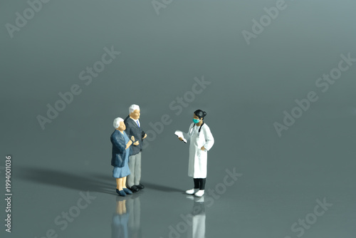 Miniature people toys conceptual photography. Elderly couple with woman doctor. Medication and health check-up concept