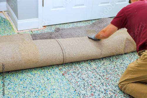 Photos Contractor is unrolling carpet in room while preparing it for installation on floor