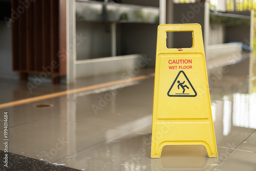 A caution wet floor sign is placed outside a restroom while cleaning is in progress, helping prevent slips and accidents, ensuring safety and awareness for visitors in a public indoor area.