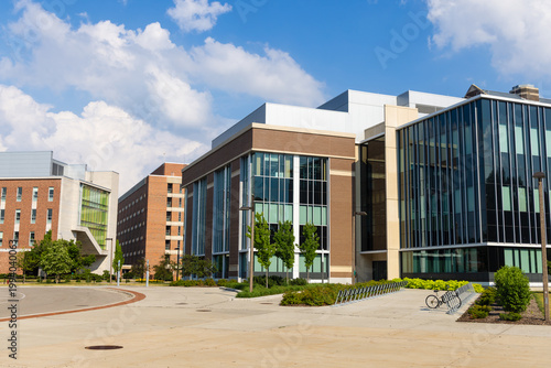 Modern university buildings framing an outdoor pathway on a sunny day