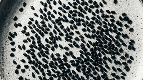 Black sesame seeds scattered on a textured grey ceramic plate
