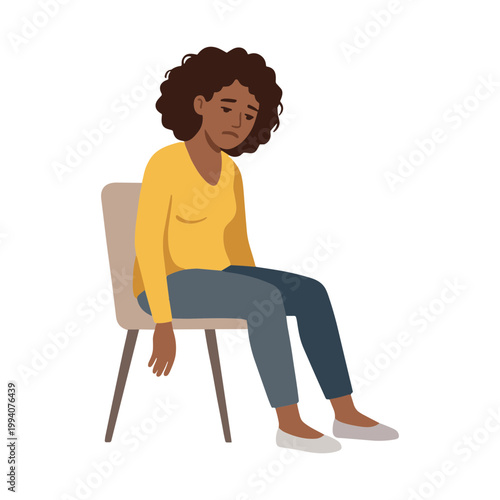 A woman sits on a chair looking down with sadness