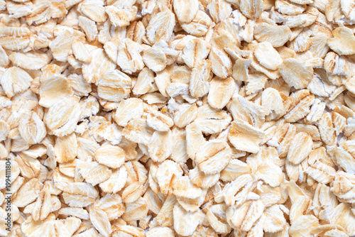 Closed-up dry organic rolled oats background in the concept of healthy eating, natural ingredients, and whole grain nutrition.