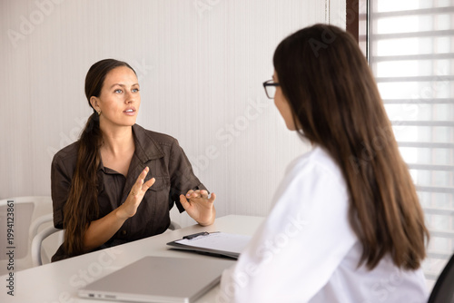 Adult Caucasian woman patient sharing health complaints, describing disease symptoms, ask about diagnosis or treatment, talks to female doctor during medical visit in clinic office. Healthcare service