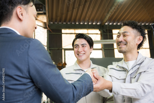 製造業の工場で握手する営業マンと作業員の信頼関係ビジネス契約や合意シーン　業務提携、協力、融資などのbtobの法人営業イメージクローズアップ