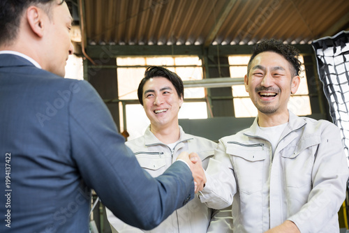 製造業の工場で握手する営業マンと作業員の信頼関係ビジネス契約や合意シーン　業務提携、協力、融資などのbtobの法人営業イメージクローズカメラ目線アップ