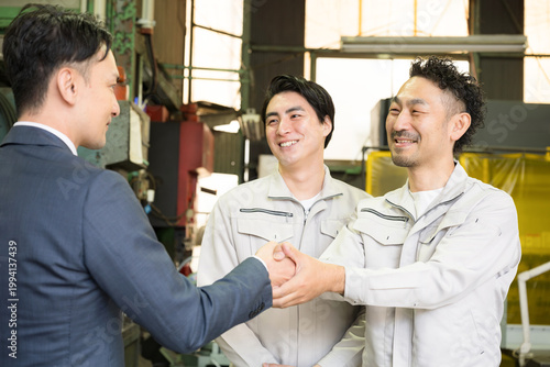製造業の工場で握手する営業マンと作業員の信頼関係ビジネス契約や合意シーン　業務提携、協力、融資などのbtobの法人営業イメージ