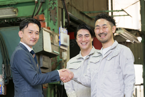 A sales representative and a factory worker shaking hands in a manufacturing plant, symbolizing a relationship of trust; scenes of business contracts and agreements; imagery of B2B corporate sales inv
