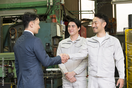 製造業の工場で握手する営業マンと作業員の信頼関係ビジネス契約や合意シーン　業務提携、協力、融資などのbtobの法人営業イメージ