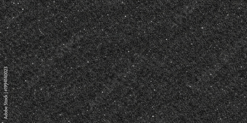 Rough dark bitumen surface creates a grainy black asphalt texture background with a weathered stone pattern on the construction pavement