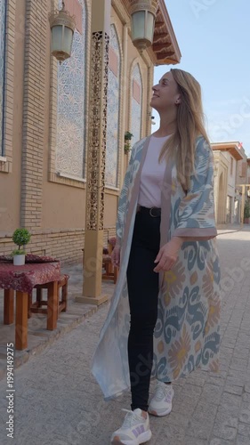 Young woman walking old city street in Tashkent with mosaic facades