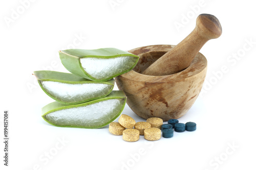 Aloe vera slices and herbal supplements with a wooden mortar and pestle on white background