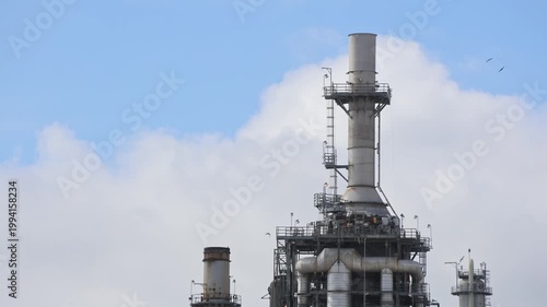 Old Oil Refinery Stack With Clouds And Birds