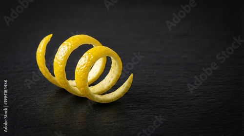 Fresh lemon peel spirals on black slate background  