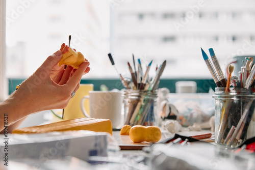 Canvastavla Hands of an artist sculpting yellow clay with tools in a bright creative studio