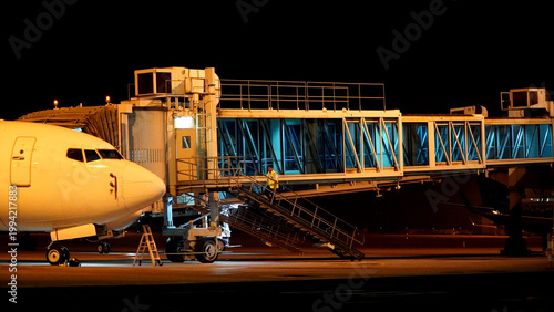 Bild auf Leinwand Side View of Illuminated Airport Jetway Gate Connector Connected to Aircraft at