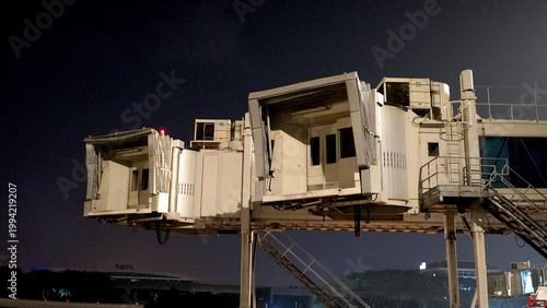 Foto Airport jet bridge or telescopic gangway at night for passenger boarding and dis