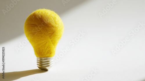 Yellow light bulb shape made of wool yarn on white background, representing creative thinking and innovative ideas