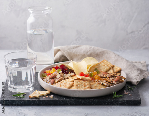 A delicious snack setup with cheese plate crackers and water glasses on a slate board