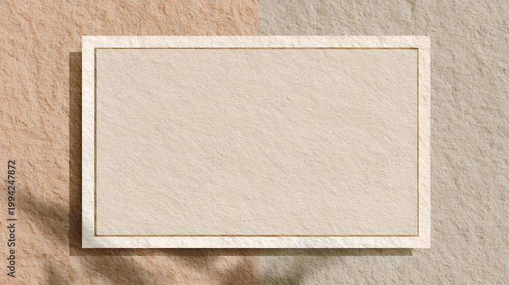 Fototapeta premium Blank beige paper frame with texture overlay, casting natural shadow on a two tone rough background, offering minimalist design space
