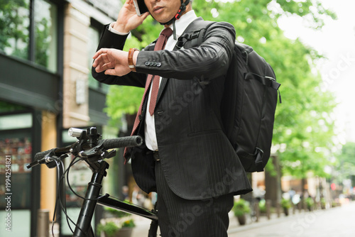 自転車通勤中にスマートフォンを確認するビジネスマン