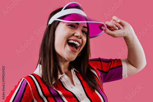 Woman wearing vibrant striped polo and pink visor