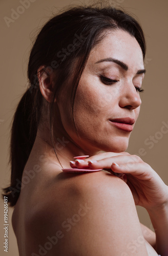 Woman using a pink exfoliating pad on shoulder