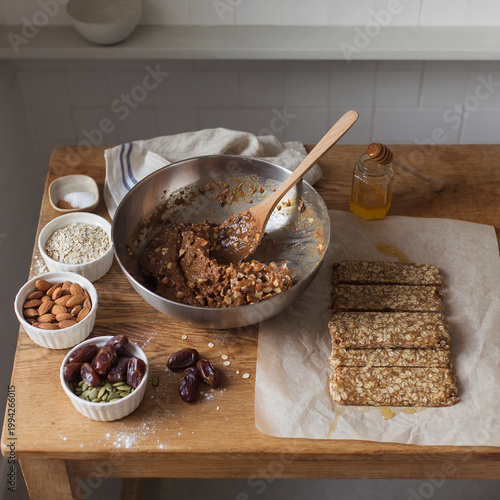 Preparing healthy homemade granola bars with nuts and dates on wooden table