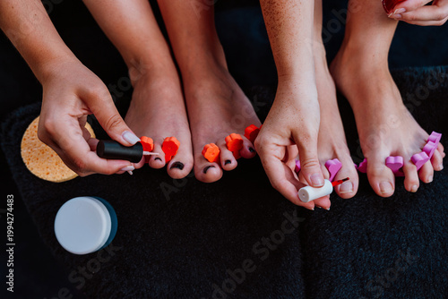 Women painting toenails with colorful nail polish at home