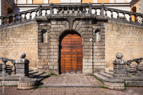 Historic wooden door at the base of a stone staircase at Villa Farnese in Caprarola, Italy. Classic Renaissance architecture with symmetrical balustrades.