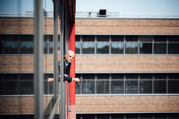 Senior businessman looking out through office window on sunny day