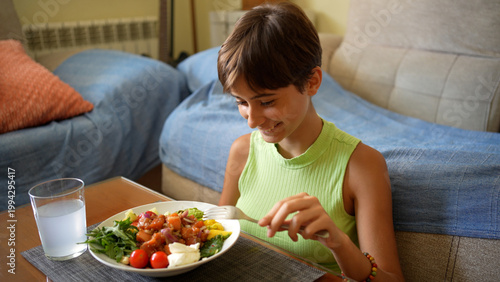Young boy happily consuming healthy and vivid vegetable salad at home in relaxed setting