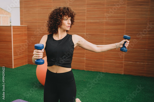 Yogainspired kneeling dumbbell raise emphasizing technique and rehabilitation on rooftop