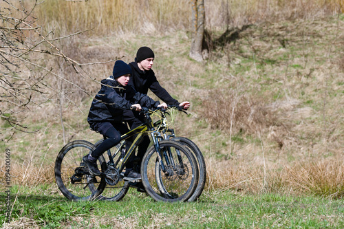 Two young people on mountain bikes enjoying a ride through a rural landscape. A sunny day of outdoor adventure.