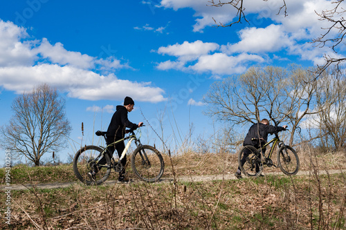 Two people on bicycles enjoy a sunny day's ride along a path.