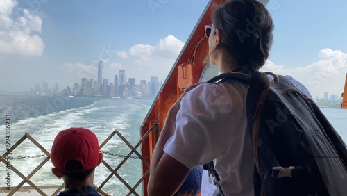 Family enjoying staten island ferry ride, mother and son pointing at lower manhattan skyline with one world trade center, bonding over iconic waterfront views and city dreams