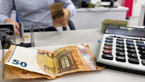 Fotografía Person handling cash and using a money counter, with euro banknotes and a calcul