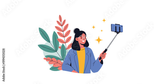 Smiling young woman with glasses and a bun hairstyle uses a selfie stick to take a photo of herself in front of a lush plant background.
