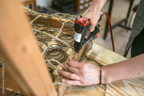 Craftswoman Attaching Upholstery Springs with Staple Gun
